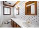 A vintage bathroom featuring dual sinks, patterned wallpaper, wood trim, and ornate fixtures at 6 Martin Ln, Englewood, CO 80113