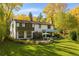 Charming two-story home with a lush green lawn, mature trees, and patio seating area perfect for outdoor entertaining at 6 Martin Ln, Englewood, CO 80113