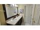This bathroom includes a vanity, dark cabinetry, framed mirror, decorative prints, and tile flooring at 12388 Jasmine St, Brighton, CO 80602