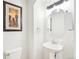 Cozy half bathroom featuring a pedestal sink, round mirror, and decorative artwork at 5129 Pasadena Way, Broomfield, CO 80023