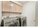 Practical laundry room featuring modern washer and dryer units and overhead cabinets at 5129 Pasadena Way, Broomfield, CO 80023