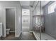 This bathroom has a modern shower with glass door, white towels, bright lighting, and gray tile walls at 6932 E 133Rd Ave, Thornton, CO 80602