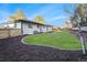 Large backyard with lush lawn, privacy fence, and landscaped retaining wall with white painted brick home in background at 8236 W 71St Pl, Arvada, CO 80004
