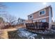 Home's backyard with a deck, partial snow cover, and privacy fence, creating a serene outdoor setting at 1099 Thornbury Pl, Highlands Ranch, CO 80129