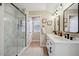 Modern bathroom featuring double sinks, large mirrors, and a sleek glass-enclosed shower with marble-like tile at 1099 Thornbury Pl, Highlands Ranch, CO 80129