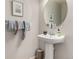 Powder room with a pedestal sink, oval mirror, and decorative towels with beaded accents at 4873 S Fultondale Way, Aurora, CO 80016