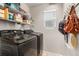 Modern laundry room equipped with black front-loading washer and dryer units and storage shelves at 4873 S Fultondale Way, Aurora, CO 80016