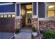 Close-up of the home's entrance highlighting stone pillars, a glass storm door, and decorative potted plants at 25 N Irvington St, Aurora, CO 80018