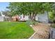 Landscaped backyard featuring a wood deck, mature tree, and a well-maintained lawn, offering privacy and serenity at 4982 S Danube St, Aurora, CO 80015