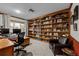 Home office boasts custom built-in shelves, a desk, and a comfortable sitting area near the window at 2090 S Gray Dr, Lakewood, CO 80227
