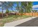Spacious backyard with a wood fence, mature trees, and a concrete patio area at 14317 Olmsted Dr, Denver, CO 80239