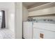 This laundry room features a washer, a dryer, shelving, and tiled floors at 12148 E Kepner Pl, Aurora, CO 80012