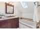 Well-lit bathroom featuring a soaking tub, a skylight, and vanity with granite counters at 16 N Pennsylvania St, Denver, CO 80203