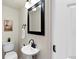Cozy half bathroom featuring a pedestal sink, dark fixtures, and a black-framed mirror at 16 N Pennsylvania St, Denver, CO 80203