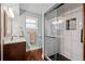 Bright bathroom featuring a vanity with sink and a glass-enclosed shower with black honeycomb floor tiles at 6402 W 81St Ave, Arvada, CO 80003