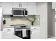 Modern kitchen with stainless steel microwave and range against stylish tiled backsplash at 6402 W 81St Ave, Arvada, CO 80003
