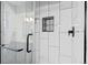 Sleek shower with white tiled walls, black honeycomb floor, black hardware and built in shelving niche at 6402 W 81St Ave, Arvada, CO 80003