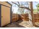 Fenced backyard featuring a wooden gate, mature tree, and partial view of the shed at 2927 W 81St Ave # B, Westminster, CO 80031