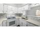 Well-lit kitchen features white cabinetry, quartz countertops, stainless steel sink, and patterned backsplash at 2927 W 81St Ave # B, Westminster, CO 80031