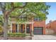 Charming red brick home featuring a cozy front porch and an attached garage, enhanced by mature trees at 2436 W Argyle Pl, Denver, CO 80211