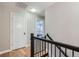 Hallway with hardwood floors, black iron railing, and white doors leading into bedrooms at 2436 W Argyle Pl, Denver, CO 80211