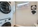 Bright laundry room with white cabinets, a window, and a stacked washer/dryer at 2436 W Argyle Pl, Denver, CO 80211