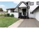 Inviting front entrance with dark wood porch, fresh white paint, and stylish black trim details at 8249 Zephyr St, Arvada, CO 80005