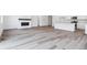 Open-concept living area featuring sleek wood-grain floors and a modern fireplace, next to the kitchen at 9112 Telluride Ct, Commerce City, CO 80022