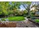 The lush backyard showcases a stone pathway, a cozy seating area, and mature trees at 7900 Crest Dr, Lakewood, CO 80214