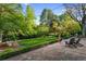 Expansive backyard with a stone patio, lush landscaping, and mature trees, providing a serene retreat at 7900 Crest Dr, Lakewood, CO 80214