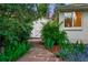 Backyard with a winding stone path and blooming flowers leading to a shed and the home's exterior at 7900 Crest Dr, Lakewood, CO 80214