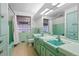 Retro styled bathroom with dual sinks, vintage tile, and large vanity mirror at 7900 Crest Dr, Lakewood, CO 80214