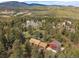 Drone view of property with home and separate garage surrounded by towering trees in a scenic, forested area at 7754 Swaps Trl, Evergreen, CO 80439