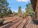 Large wood deck with railings overlooking a treed yard with barbecue grill, and string lights at 7754 Swaps Trl, Evergreen, CO 80439