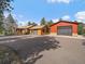 Rustic home showcasing a spacious driveway and a detached garage or workshop, surrounded by mature trees at 7754 Swaps Trl, Evergreen, CO 80439