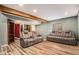 Finished basement with wood-look floors, exposed beam, and two reclining couches at 4871 S Dunkirk Way, Centennial, CO 80015