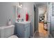This is a bathroom with blue vanity, a toilet, and a view to another room through an open door at 4855 E Atlantic Pl, Denver, CO 80222