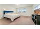 Minimalist bedroom with a blue headboard, neutral bedding, and ample natural light from two windows at 18552 E 54Th Ave, Denver, CO 80249