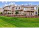 Inviting townhomes with manicured lawn, brick retaining wall, and black metal fencing at 1818 S Quebec Way # 4, Denver, CO 80231