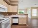 Bright kitchen features white appliances, light wood cabinets, and an open layout to the living area at 8371 S Upham Way # 103, Littleton, CO 80128