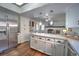 Bright kitchen featuring white cabinets, stainless steel appliances, and an open floor plan leading to the living area at 7006 S Miller Ct, Littleton, CO 80127