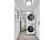 Convenient laundry area featuring a stacked washer and dryer with a water heater on laminate floor at 1000 S Perry St, Denver, CO 80219