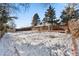 View of the backyard with snow, storage shed, and home at 420 Racine St, Aurora, CO 80011