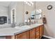 Well-lit bathroom featuring double sinks, light wood cabinets, and large mirrors at 3383 Willowrun Dr, Castle Rock, CO 80109