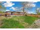 View of the backyard featuring a grassy area, wooden fence, and mature trees at 1772 S Pierce St, Lakewood, CO 80232