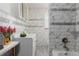 Bathroom with modern white and gray tiling, a large vanity, and a combination shower and tub at 8110 Ivy St, Commerce City, CO 80022
