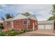 Charming red brick home with a well-maintained yard and a detached two-car garage in the backyard at 8110 Ivy St, Commerce City, CO 80022