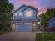 Charming two-story home featuring blue siding, brick accents, and a well-manicured front yard at twilight at 6447 St Vrain Ranch Blvd, Longmont, CO 80504