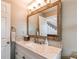 Bathroom featuring light marble vanity, a framed mirror, and a view of the staircase at 895 Antelope W Dr, Bennett, CO 80102