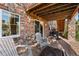 A covered stone patio with two chairs, a fire pit, and a grill, perfect for outdoor entertaining at 6310 S Ider St, Aurora, CO 80016